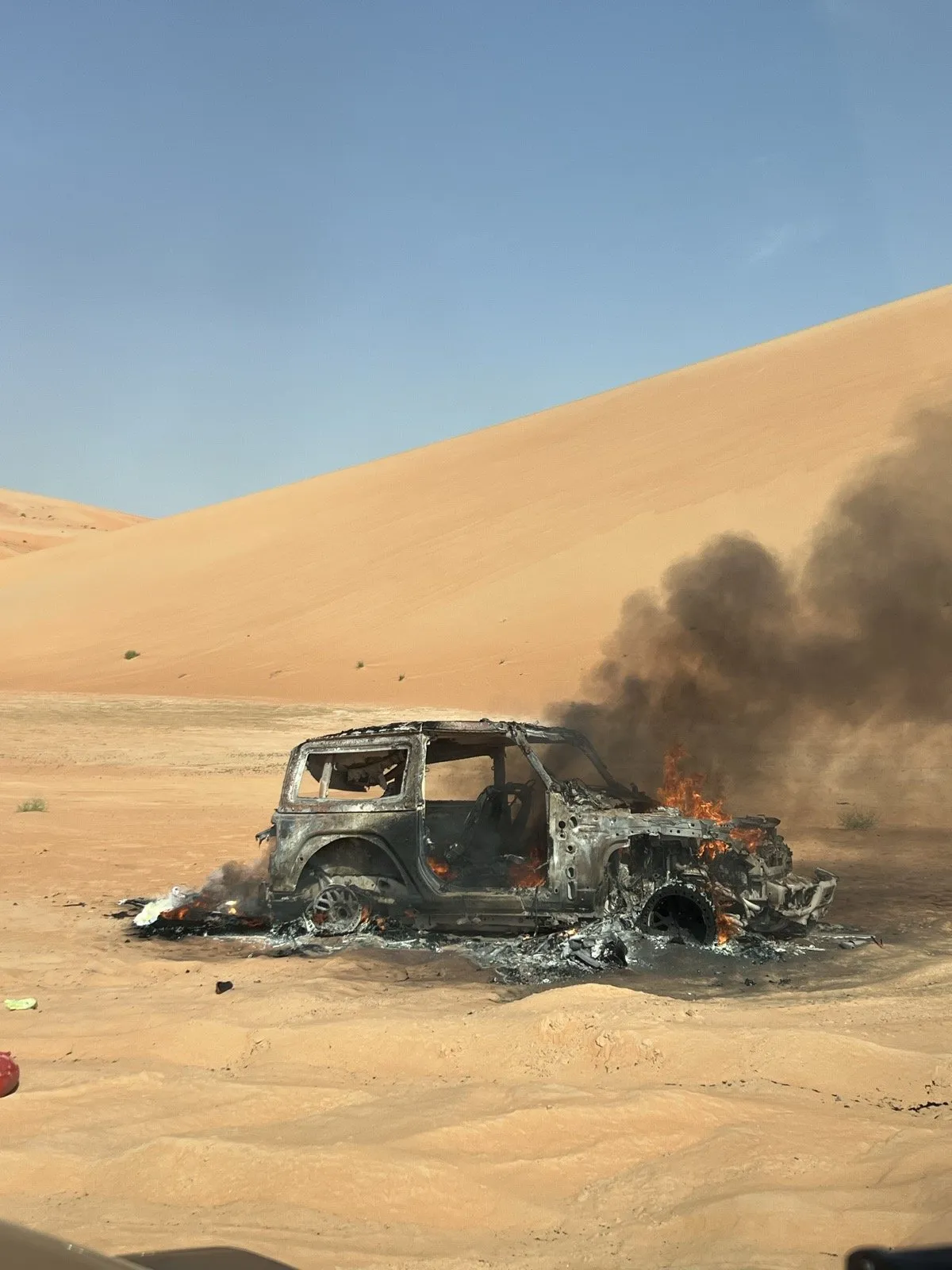The burnt-out shell of a 4x4 on the sand at Al Quaa