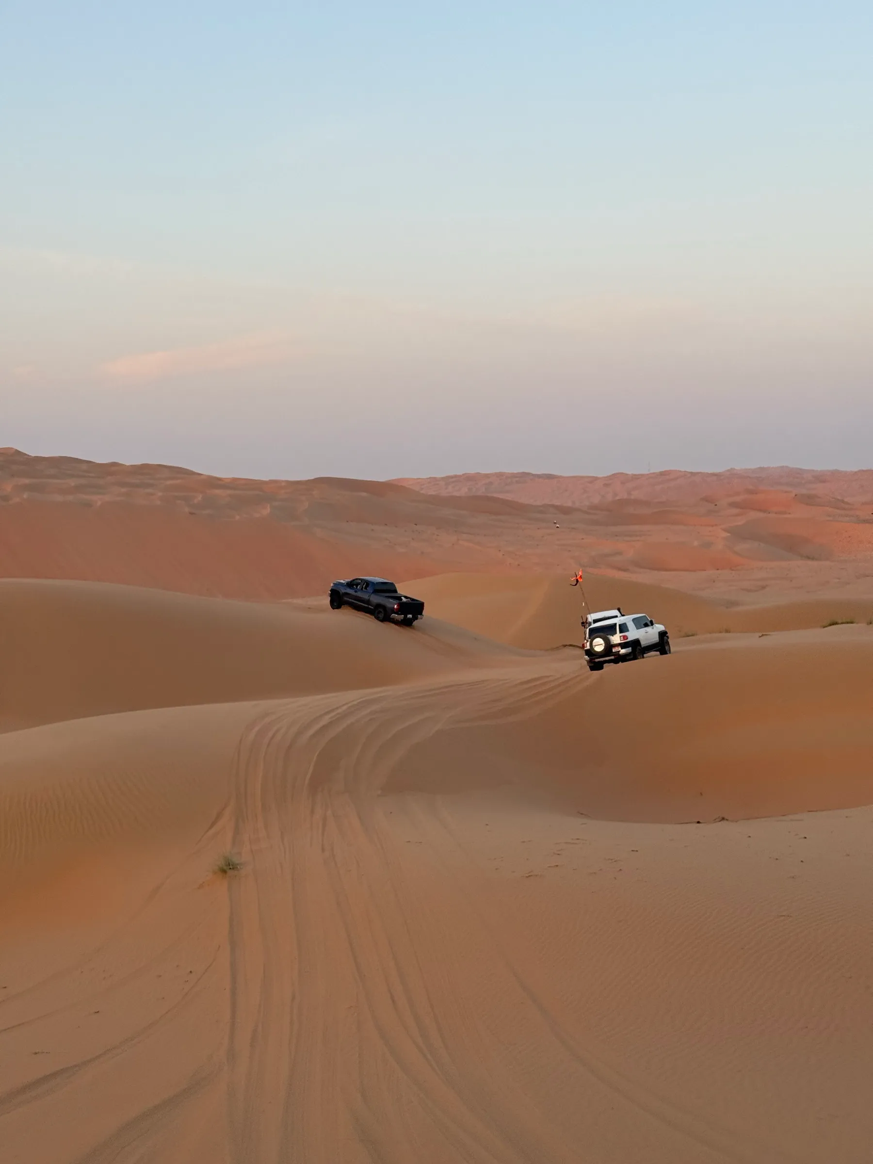 Two 4x4s on gentle dunes near Dubai at dusk