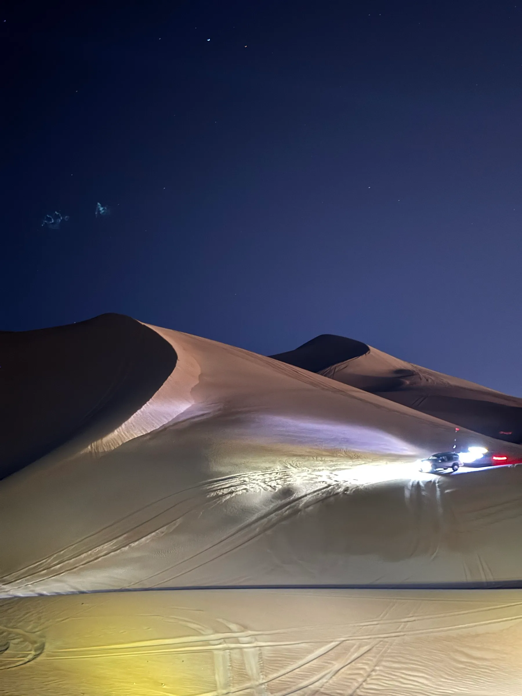 Headlights lighting a dune ridge after dark. Conditions like this mean you turn back.