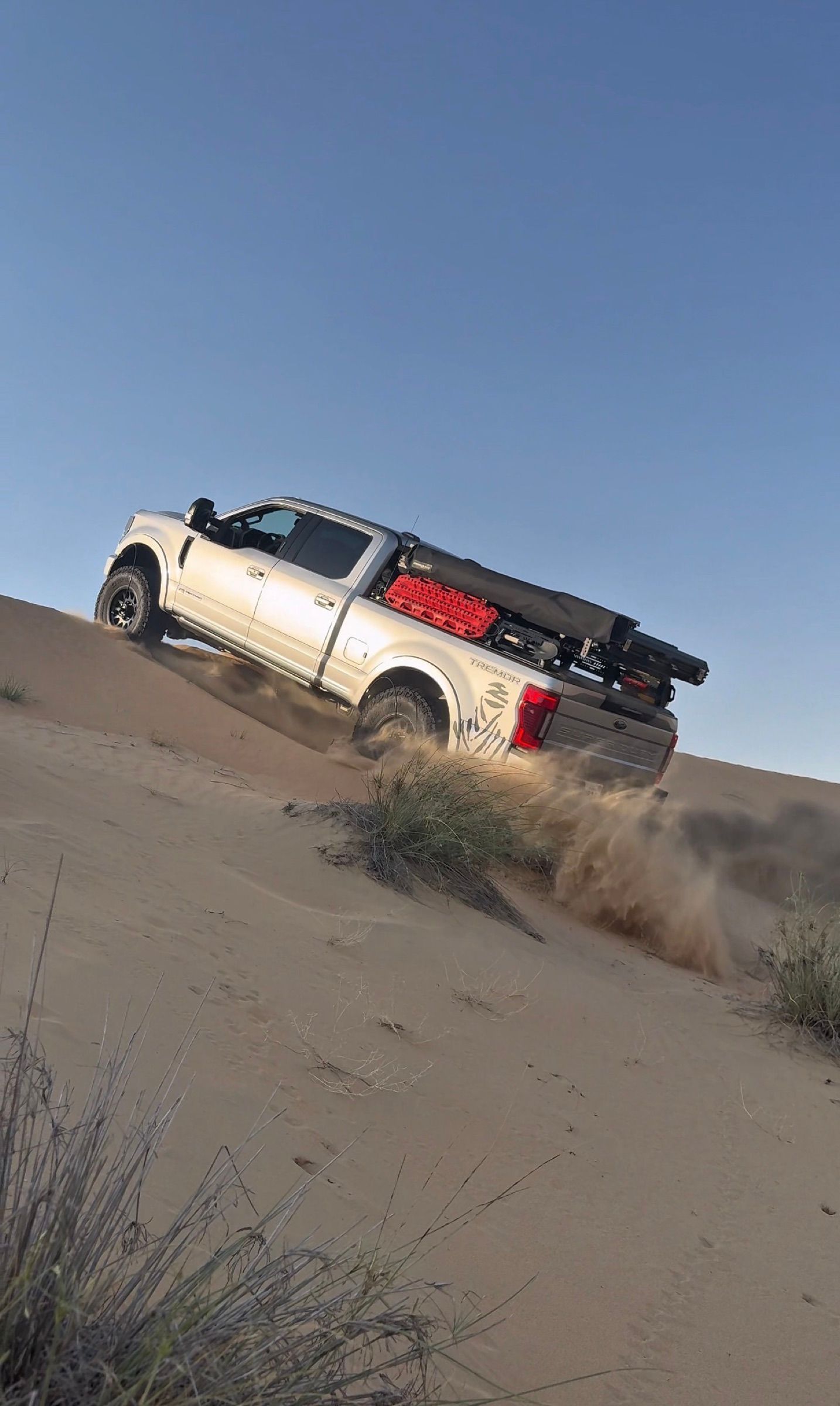 Recovery boards under a pickup’s rear tyres as it climbs out of soft sand