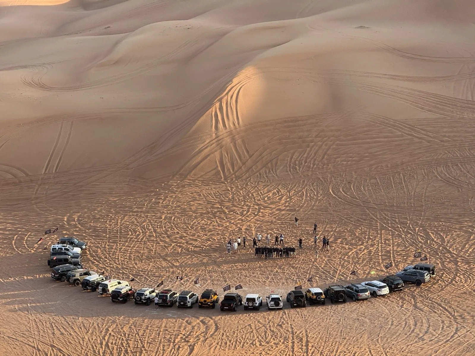 A club convoy parked in a circle inside a dune bowl during the briefing