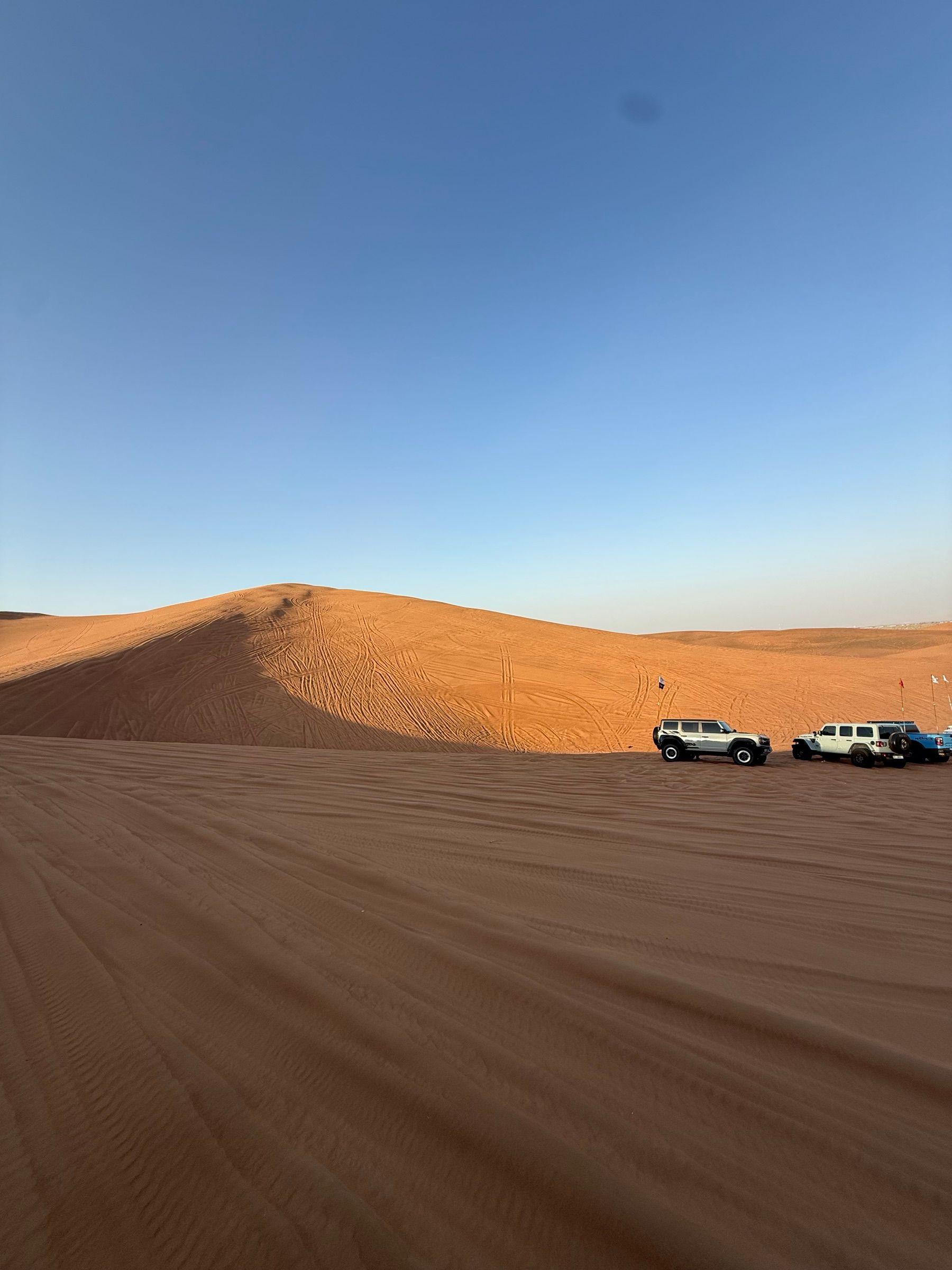 Two SUVs parked at the edge of the dunes before a drive