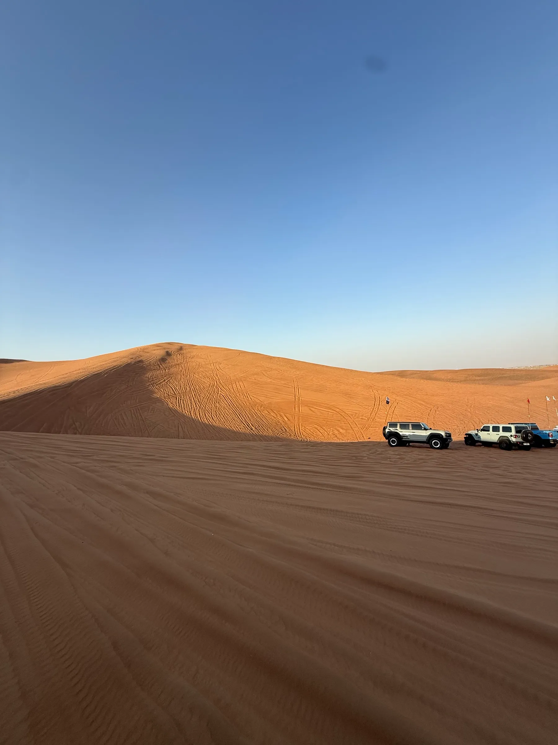 Two 4x4s parked on firm ground at the edge of the dunes. This is where you air down before driving on sand.