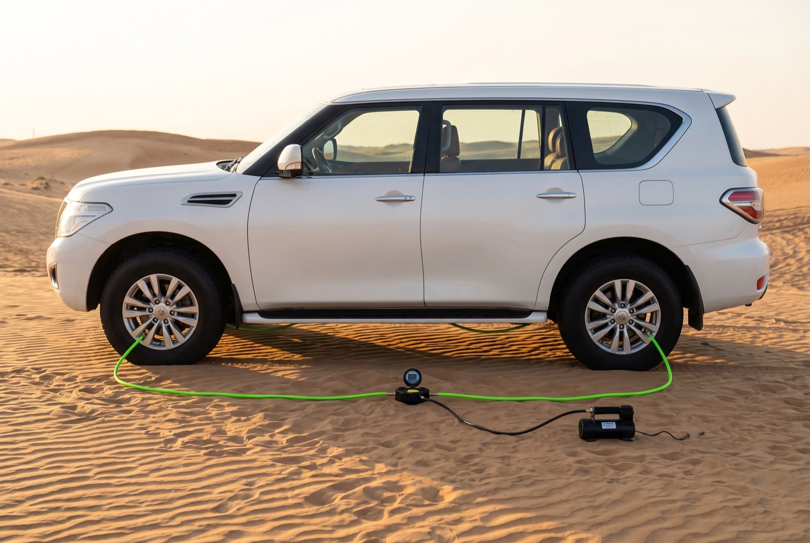 Visualisation: a white 4x4 on the dunes, one green hose on each wheel, all four running to one gauge hub and a compressor.