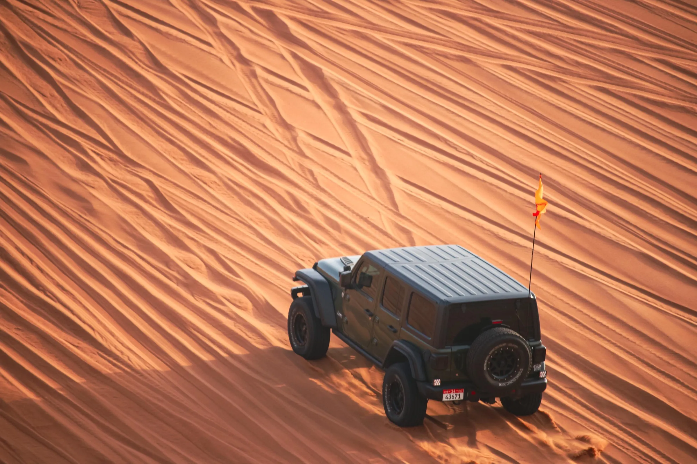 A near-stock Wrangler descending a steep golden dune face